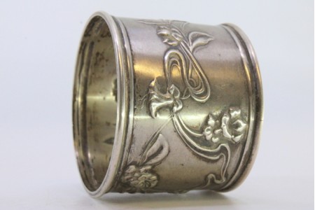 Argola de guardanapo em prata com motivos florais relevados envolvendo cartela para monograma.